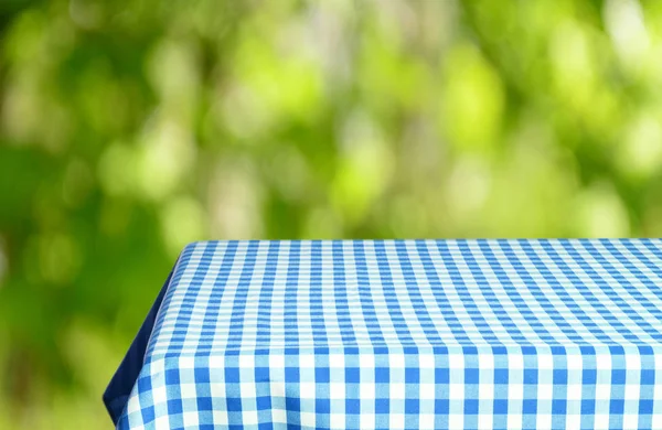 Leerer Tisch Mit Farbig Karierter Tischdecke Und Unscharfem Natürlichen Hintergrund — Stockfoto