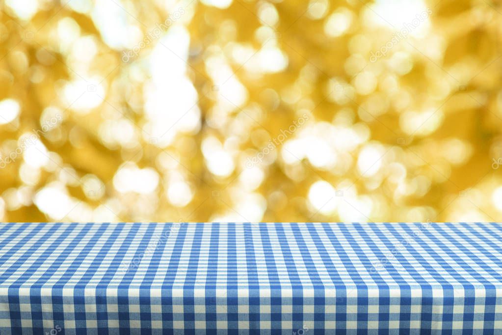 Empty table with color checkered tablecloth and blurred natural background