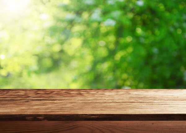 Empty wooden table with blurred natural background