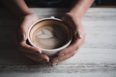 Bir fincan kahve kafede masada holding bir kadının eller görüntüsünü üstten görünüm