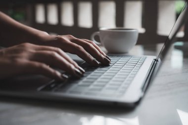 Laptop klavyesinde çalışan ve daktilo kullanan bir kadının yakın plan fotoğrafı.