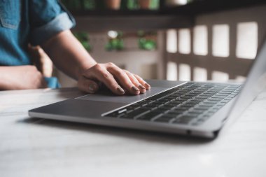 Masadaki dizüstü bilgisayarda çalışan ve daktilo kullanan bir kadının yakın plan resmi.