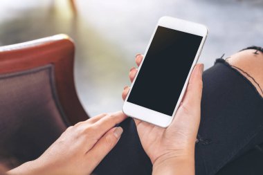 Kadının görüntüsünü mockup kafede otururken holding beyaz cep telefonu ile boş siyah masaüstü ekran eller