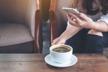 Portre resim bir kadın tutarak, kafede kahve yudumlarken bir akıllı telefon dokunmak ve kullanma