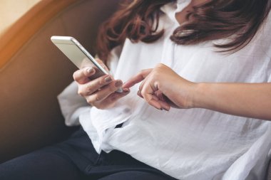 Akıllı bir telefonu tutan, kullanan ve dokunan bir kadının yakın plan görüntüsü