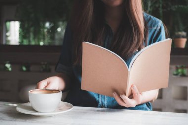 Modern kafede kahve yudumlarken bir kitap okuma bir Asyalı closeup görüntü 