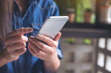 Akıllı bir telefonu tutan, kullanan ve dokunan bir kadının yakın plan görüntüsü