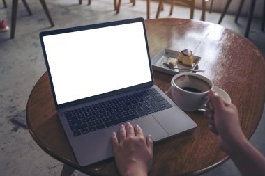 Modern kafede kahve içerken boş beyaz ekran kullanan ve daktilo kullanan bir kadının görüntüsü.