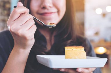 Mutlu bir kadın tutarak closeup görüntü ve peynir pasta cafe kaşıkla yemek zevk