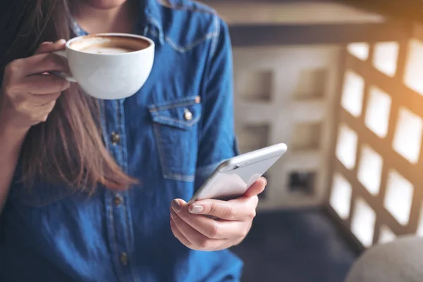 Bir Kadının Elinde Tuttuğu Kahve Içerken Akıllı Bir Telefona Dokunduğu — Stok fotoğraf