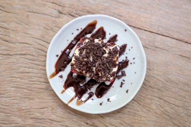 Kırmızı kadife kek krem ve beyaz seramik plaka üzerinde ahşap masa çikolatada bir parçasının üstten görünüm görüntüsü