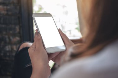 Kafede otururken boş masaüstü ekran ile beyaz cep telefonu tutan kadınların ellerinin görüntüsü