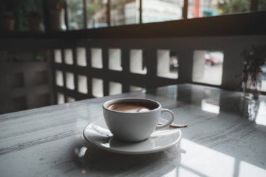 Kafedeki masada beyaz bir fincan sıcak kahvenin yakın plan görüntüsü.