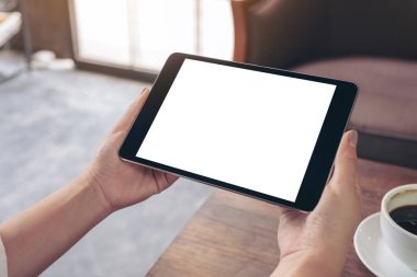 Bir kadının görüntüsünü mockup holding siyah tablet pc ile masada kahve fincanı ile beyaz boş ekran eller 
