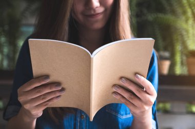Portre resim güzel bir Asya kadının modern kafede bir kitap okuma 