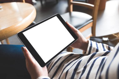 Kafede otururken siyah tableti beyaz masaüstü ekran ile tutan kadınların ellerinin görüntüsü