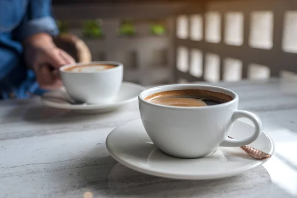 カフェのテーブルでコーヒー熱いラテの白いカップを握っている手のクローズ アップ画像 — ストック写真