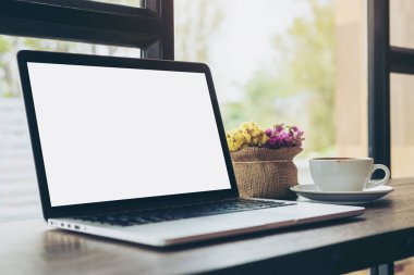 Mockup görüntü boş beyaz ekran, bir fincan kahve ve çiçek vazo modern loft Cafe ahşap tablo ile dizüstü