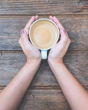 Bir fincan kahve ahşap antika masa üzerinde tutan kadının elleri görüntüsünü Üstten Görünüm