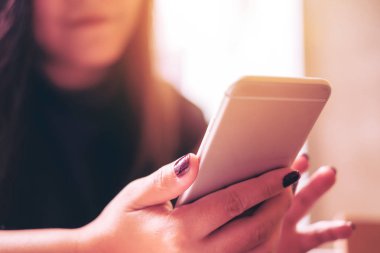 Modern kafede akıllı telefon kullanan gülen suratlı güzel bir Asyalı kız.