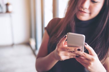 Modern kafede akıllı telefon kullanan gülen suratlı güzel bir Asyalı kız.