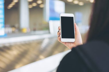 Bir kadın tutarak ve Bagaj talep havaalanında beklerken cep telefonunuzun 