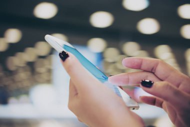 Bir kadının dokunaklı el ve parmak süre ayakta ve Bagaj talep havaalanında bekleyen akıllı telefon sürgülü