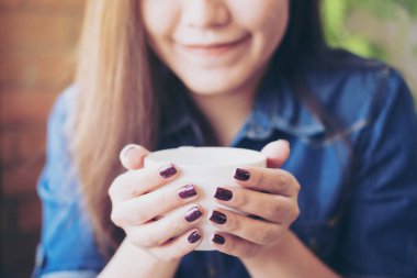 Holding ve iyi hissediyorum ile sıcak kahve içme Asyalı kadın portre görüntü