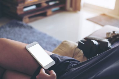 Beyaz cep telefonu ile kadının uyluk evi planda gri halı ile boş beyaz ekran görüntüsünü mockup