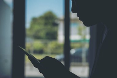 Holding ve akıllı telefon içinde ev kullanarak bir kadın siluetleri