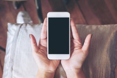 Yastık ile ahşap zemin arka plan üzerinde beyaz cep telefonu ile boş siyah perde holding eller mockup görüntü
