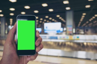 Mockup görüntü bir süre ayakta ve Bagaj talep havaalanında bekleyen boş yeşil ekran ile beyaz cep telefonu tutan bir adam