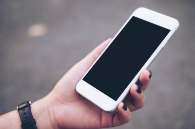 El beyaz cep telefonu ile boş siyah perde ile tutarak mockup görüntü gri renk arka plan bulanıklık 