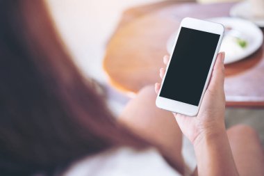 Antika ahşap kafede boş siyah perde ile beyaz cep telefonu tutan el mockup görüntü