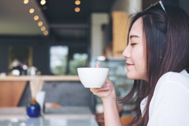 Portre resim güzel bir Asya kadının kokusu ve modern kafede iyi duygu ile sıcak kahve içme