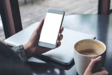 Cep telefonu ile Cafe ahşap masa latop ve kahve Kupası ile boş beyaz ekran görüntüsünü mockup