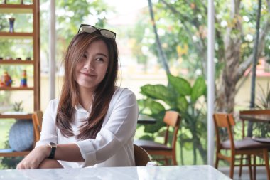 Gülen yüz ve duygu iyi yeşil doğa geçmişi olan kafede oturan ile güzel Asyalı kadın portre portre görüntü