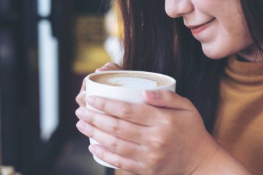 Holding ve vintage kafede sıcak kahve bakarak Asyalı kadın portre resmi