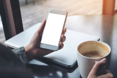 Cep telefonu ile Cafe ahşap masa latop ve kahve Kupası ile boş beyaz ekran görüntüsünü mockup