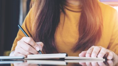 Görüntü Cafe ahşap masa üzerinde kupa kahve ile defter üzerinde yazma bir kadının kapatın