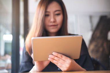 Güzel bir Asyalı kadın tutarak ve modern kafede tablet PC'yi kullanma