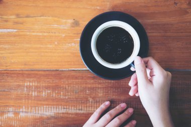 Bir fincan sıcak kahve ahşap masa arka planda tutan bir el görüntüsünü üstten görünüm