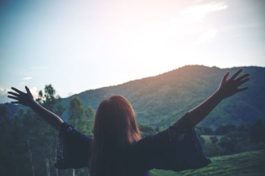 Bir kadın açmak geri duran ve doğa ve dağ arka plan ile Kol germe