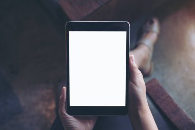 Kadının el modern kafede uyluk ile beton zemin arka plan üzerinde siyah tablet pc boş beyaz ekran ile tutarak mockup görüntü