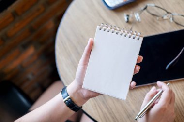 Ofiste ahşap tabloda boş defter tablet ile tutan bir kadın görüntüsünü üstten görünüm