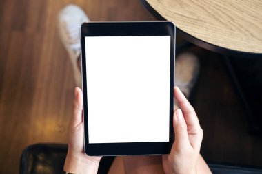 Kadının el modern kafede uyluk ile ahşap zemin arka plan üzerinde siyah tablet boş beyaz ekran ile tutarak mockup görüntü