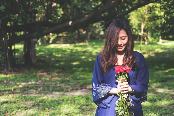 緑の自然の背景の赤いバラのブーケを持ったアジア女性 — ストック写真