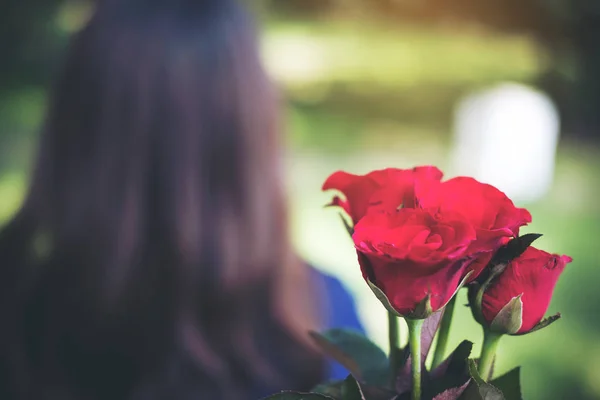 一个女人从红颜色的玫瑰花中转回来 自然背景 — 图库照片