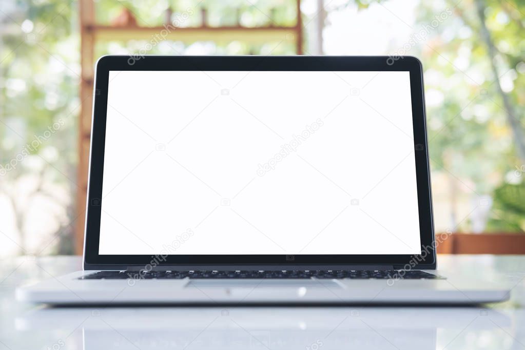 Mockup image of laptop with blank white screen on marble table in modern cafe with nature background