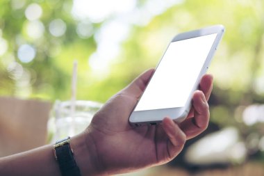 Bir kadın tutarak ve açık ve yeşil doğa arka plan boş ekran ile beyaz akıllı telefon kullanarak mockup görüntü 